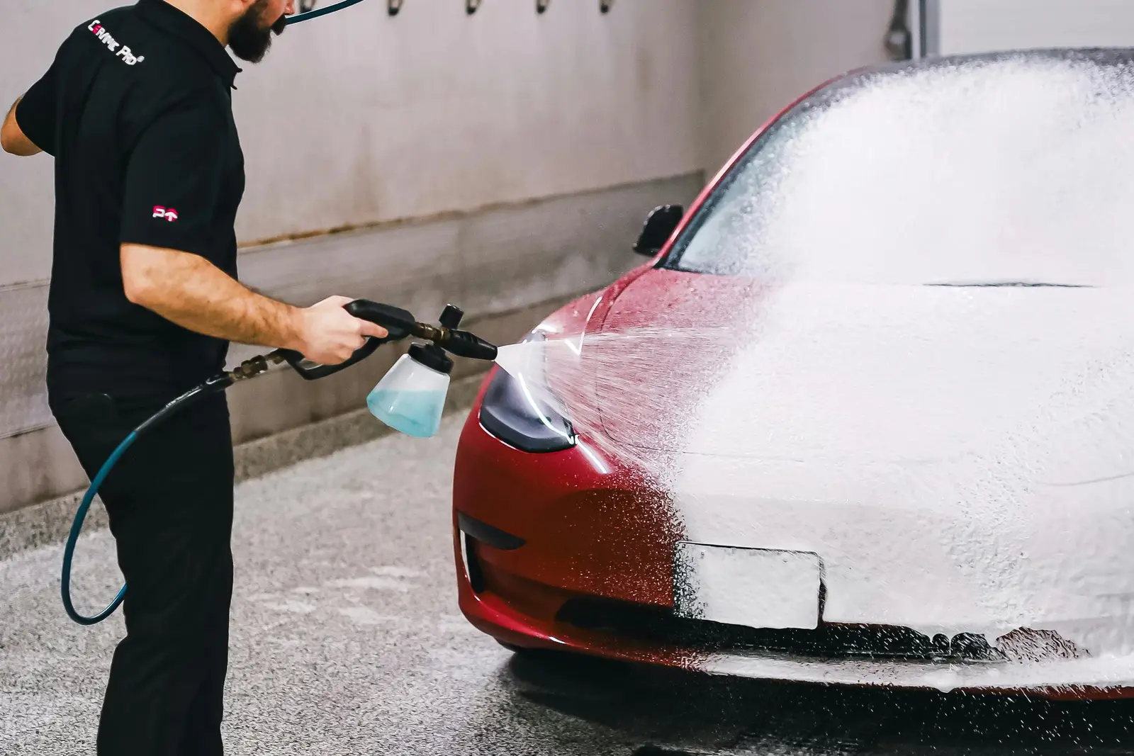 A car covered in wash foam being cleaned by hand