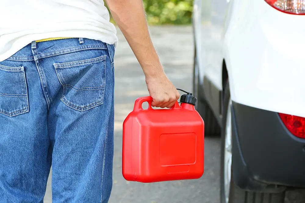 Someone carrying a fuel can to a car stopped at the roadside